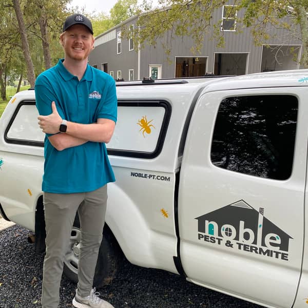 Noble Pest & Termite technician beside a noble-pt.com branded truck
