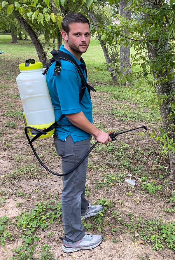 Noble technician applying a targeted treatment with a backpack sprayer